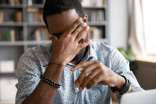 A man holding his glasses and covering his eyes