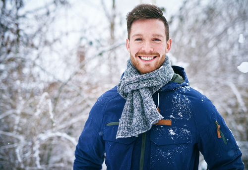 man standing outside while it snows